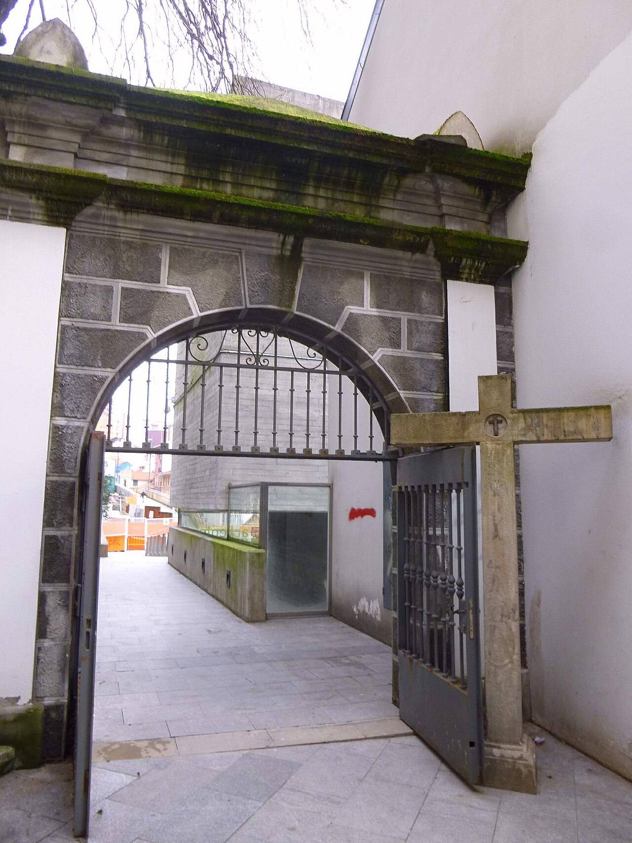 Acceso a un museo arqueológico con arco de piedra y puerta de hierro