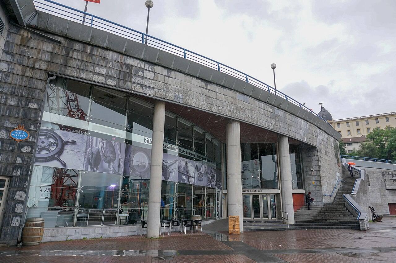 Exterior de un museo marítimo junto al agua con fachada de vidrio